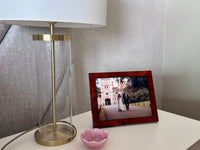 A decorative table lamp and a pink bowl beside a photo frame featuring a couple on their wedding day in a scenic backdrop. All Photograph Frames.
