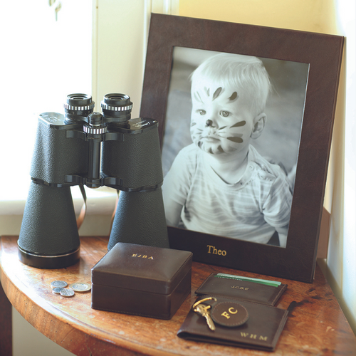 Chelsea Landscape Leather Photo Frame 10x8 displaying a child's photo, surrounded by binoculars and personal items.